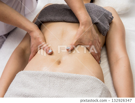 Beautiful young woman enjoying massage in spa salon. Cosmetology 132926347