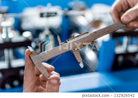 Male hands hold vernier caliper and measure steel collar. 132926542