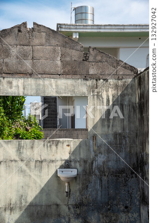 A house left in the process of being demolished, with concrete walls and a sink remaining 132927042