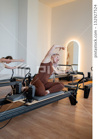 Pilates group of Women doing mermaid exercise in a sunlite modern studio, embodying calm, focus, and strength. 132927524