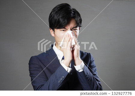 Businessman blowing his nose black background 132927776