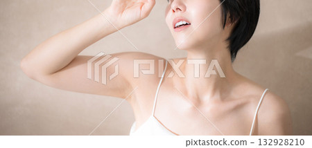 一位女子在粉米色背景下被陽光刺得睜不開眼。畫麵包含紫外線、太陽和防曬乳的元素。橫幅上沒有臉部。 132928210