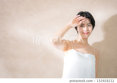 一位女士在粉米色背景下,因陽光刺眼而感到擔憂。圖片展現了紫外線、太陽和防曬乳。 一位女士在粉米色背景下,因陽光刺眼而感到擔憂。圖片展現了紫外線、太陽和防曬乳。 132928212