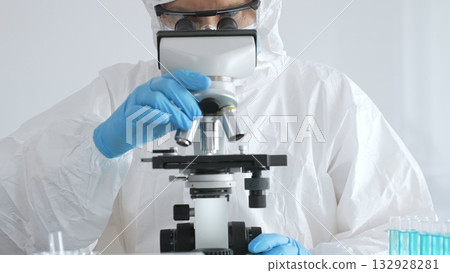 Medical virologist in protective hazmat gear analyzing samples, researching viral vaccine development within sterile pharmaceutical laboratory setting 132928281