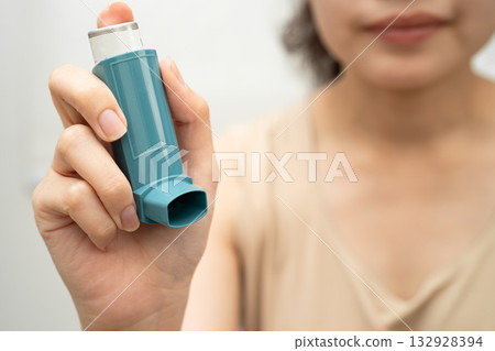Asthma and chronic obstructive pulmonary disease COPD, Asian woman using metered dose inhaler MDI. Asthma and chronic obstructive pulmonary disease COPD, Asian woman using metered dose inhaler MDI. 132928394