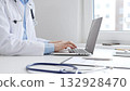 Doctor woman is typing on a laptop with a stethoscope, medical record, and pen on the desk in a bright medical office, showcasing healthcare technology and medical documentation. Medicine concept 132928470