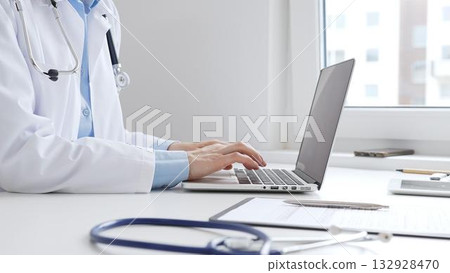 Doctor woman is typing on a laptop with a stethoscope, medical record, and pen on the desk in a bright medical office, showcasing healthcare technology and medical documentation. Medicine concept Doctor woman is typing on a laptop with a stethoscope, medical record, and pen on the desk in a bright medical office, showcasing healthcare technology and medical documentation. Medicine concept 132928470