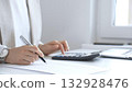 Businesswoman is calculating annual tax using calculator and taking notes in the office, managing domestic budget and checking financial documents. Audit and taxes in business 132928476