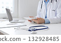 Closeup of blue stethoscope is lying on the table near female doctor reviewing prescription on digital tablet, representing digital healthcare workflow in contemporary medical setting. Medicine 132928485