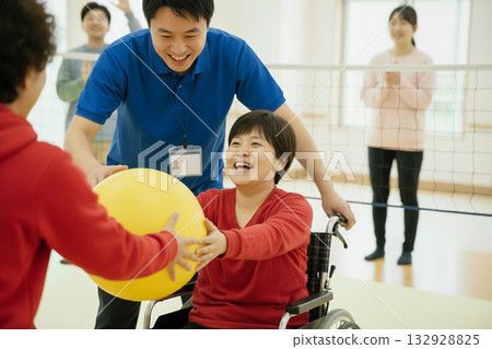 Support staff and users smiling as they play ball at a facility for people with disabilities_Recreation No portrait rights 132928825