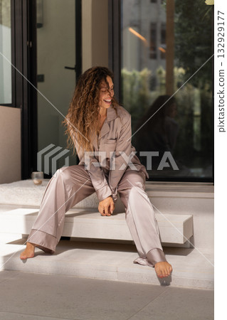Woman in pajamas sitting near window enjoying 132929177