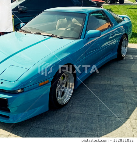 a bright blue sports coupe with tuning and a low profile on paving stones 132931052