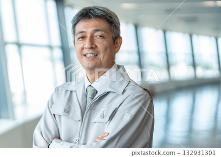 一個穿著工作服、雙臂交叉的男人 一個穿著工作服、雙臂交叉的男人 132931301