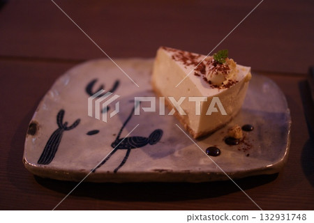 一塊起司蛋糕,配上鮮奶油和可可粉,放在陶瓷盤上。 一塊起司蛋糕,配上鮮奶油和可可粉,放在陶瓷盤上。 132931748