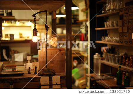 A warm cafe space with a counter decorated with antique lamps and flowers 132931750