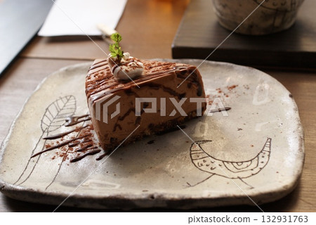 一塊淋著巧克力醬的巧克力慕斯蛋糕，盛裝於日式陶瓷盤中。 132931763