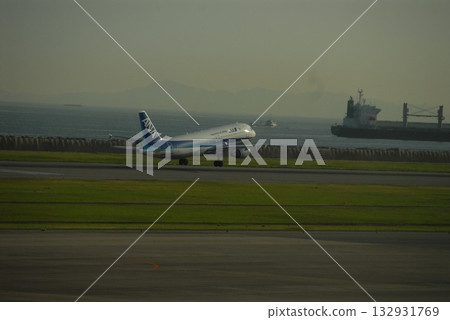 一架全日空飛機起飛，一艘貨輪在海上航行，這是從斜角拍攝的畫面。 132931769
