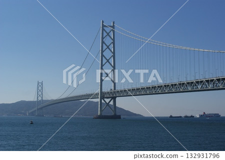 The elegant suspension bridge structure of the Akashi Kaikyo Bridge stands out against the blue sky and sea 132931796