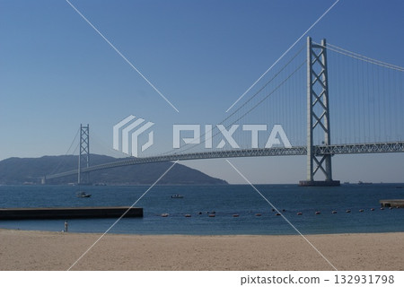 一艘小船漂浮在平靜的水面上，與明石海峽大橋交相輝映，構成一幅和諧的畫面。 132931798