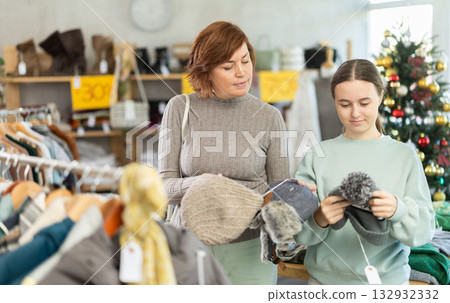 In sales area of store during Christmas sale, woman with teen daughter customer choose hat In sales area of store during Christmas sale, woman with teen daughter customer choose hat 132932332