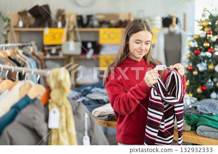 Teenage girl chooses a sweater in fashion boutique. 132932333