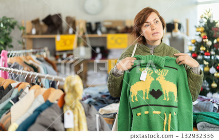 Woman picks up clothes and chooses sweater, New Year Eve sale Woman picks up clothes and chooses sweater, New Year Eve sale 132932336