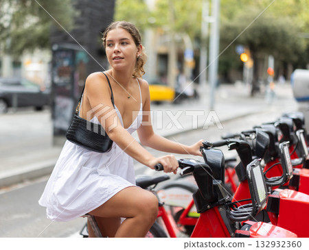 Young girl taking red bicycle from Bicing rental station 132932360