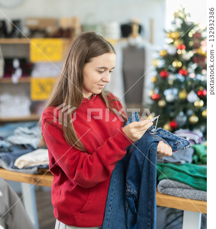 Teenage girl chooses jeans trousers in clothing store 132932386