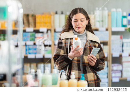 Young woman chooses cream at pharmacy Young woman chooses cream at pharmacy 132932455
