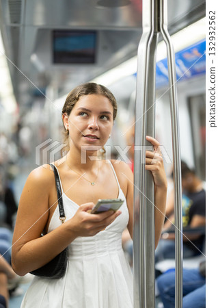 Positive young girl standing on wagon holding phone in hand Positive young girl standing on wagon holding phone in hand 132932562