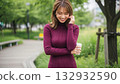 A woman in a burgundy knit dress smiling with a cup of coffee in her hand 132932590