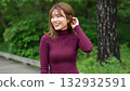 A woman in a burgundy knit dress with her hair pulled back and smiling 132932591