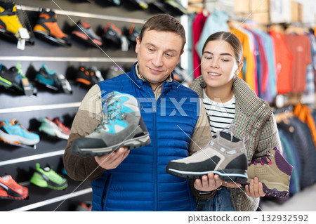 Man with daughter chooses winter trekking cross shoes 132932592