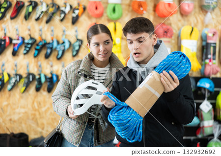 Guy and girl view rope cable for climbing and evaluate its thickness Guy and girl view rope cable for climbing and evaluate its thickness 132932692