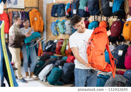 Buyer guy chooses summer backpack in store for hikes 132932695
