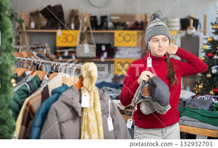 Teen girl try on winter hat in front of mirror in clothes store Teen girl try on winter hat in front of mirror in clothes store 132932701