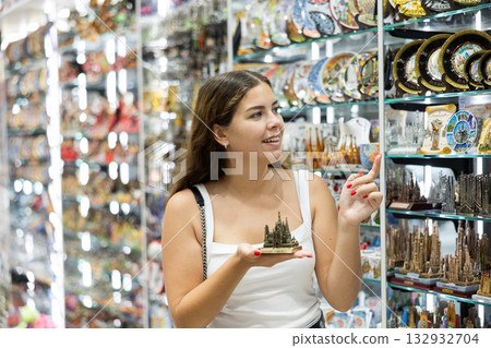 Interested young woman viewing souvenirs symbolizing Barcelona Interested young woman viewing souvenirs symbolizing Barcelona 132932704
