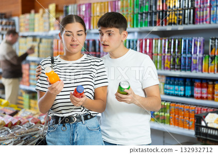 Young married couple chooses drink bottle in store to buy them Young married couple chooses drink bottle in store to buy them 132932712