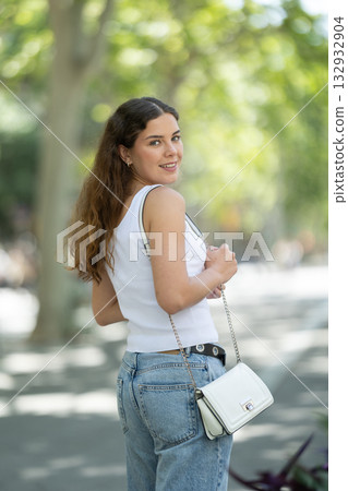 Young smiling girl walks along city street Young smiling girl walks along city street 132932904