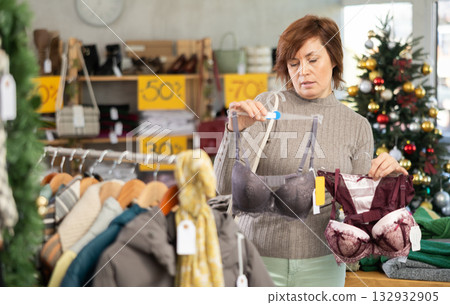 Woman picks up clothes and chooses bra, New Year Eve sale Woman picks up clothes and chooses bra, New Year Eve sale 132932905