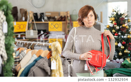 Woman is busy looking at clothes items in store, she choose eco leather handbag. 132932934