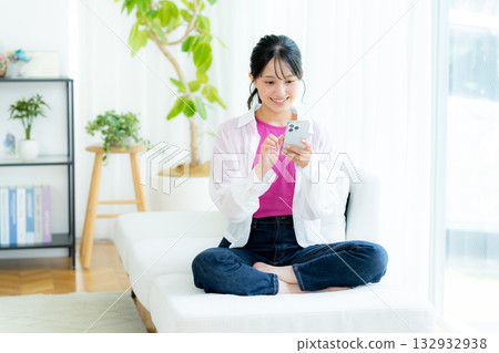 A young woman operating a smartphone in a room A young woman operating a smartphone in a room 132932938
