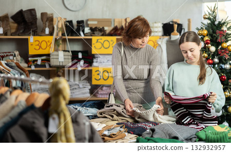 Woman chooses fashionable sweater for winter season in shop 132932957