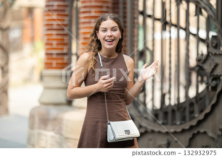 Young woman standing near the metal fence 132932975