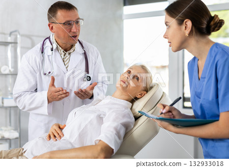 Male beautician giving consultation to woman patient with mirror in aesthetic clinic Male beautician giving consultation to woman patient with mirror in aesthetic clinic 132933018