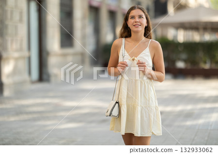 Young woman looks around on city street Young woman looks around on city street 132933062
