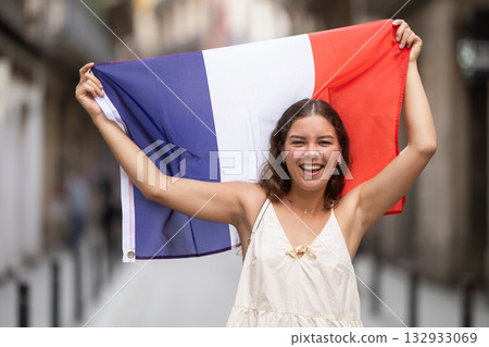 Woman waving France flag on street of summer European city Woman waving France flag on street of summer European city 132933069