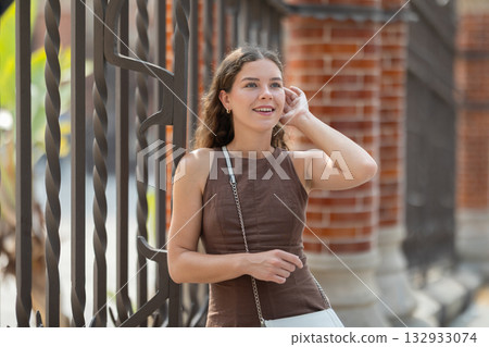 Young woman standing near the metal fence 132933074