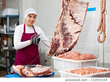 Smiling female butcher preparing big piece of beef meat in butcher shop Smiling female butcher preparing big piece of beef meat in butcher shop 132933104