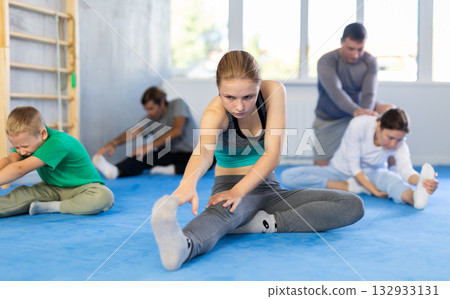 Parents with children family perform warm-up exercises and legs stretching Parents with children family perform warm-up exercises and legs stretching 132933131
